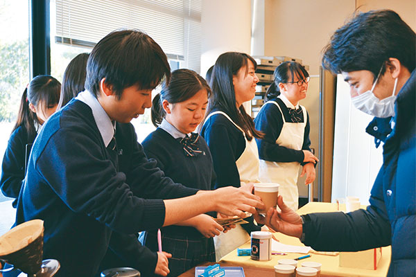 中学入試の会場でもお店を出し、ドリップパックのコーヒーを提供しました。中央が稲田さん。