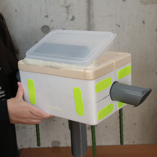 機械電子工学科の学生たちが製作中の気象観測機器『SOY』。機器全体の素材は発泡スチロールで、下部に向かって出るパイプの中にセンサーが組み込まれる予定で、これにより土壌の水分量を測るというもの。上部にはソーラーパネルを備えています。