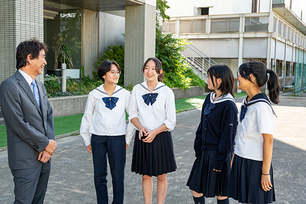 朝は正門に立って登校する生徒たちを迎えるなど、積極的に交流を図る榎並校長は、生徒にも親しまれています。写真は取材時に通りかかった留学コースの生徒たち。