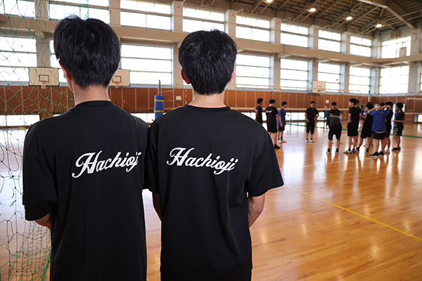 体育館にて。男子バレーボール部の練習ユニフォームを着て練習を見守る2人。