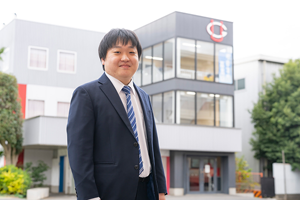 吹奏楽部の部室棟前で。現在、江丸先生は同部の顧問も務めています。