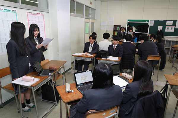 クラスメートに向けて、探究の成果（途中経過）を発表するSさんたち。