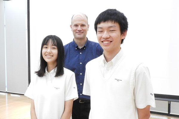 お話を伺ったハウズ先生とAさん（中3）・Hさん（中2）。イングリッシュキャンプが実施された『集会室』にて。3人は日頃から英語でコミュニケーションをとっているそうです。