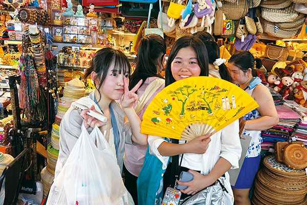 竹細工や小物などが雑多に飾られた土産物店で、記念撮影をする生徒たち。