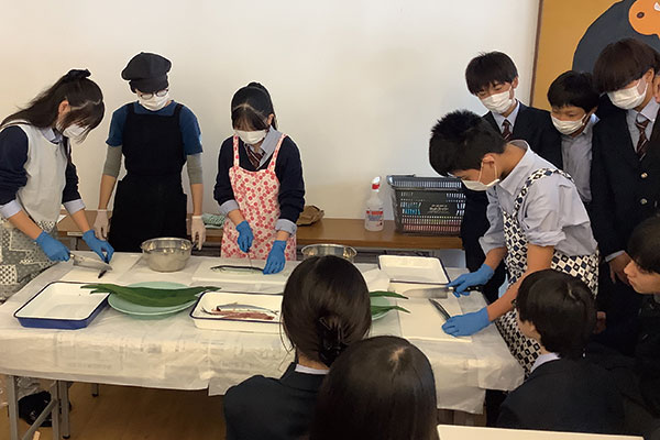 中2生はカフェテリアの管理栄養士の指導のもと、さんまのさばき方を学びます。さばいたさんまは、その日のランチで提供されます。