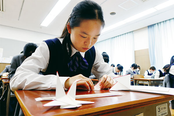 生徒が皆敷を折っている様子。皆敷とは、料理や食材を盛る際に、器の上に敷くものの総称です。